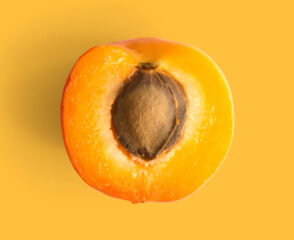 Half apricot with seed on orange background.