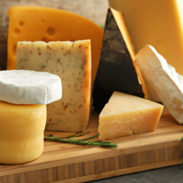 Assorted cheeses on a wooden board display.
