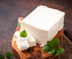 Block of feta cheese with parsley garnish.