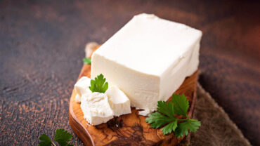 Block of feta cheese with parsley garnish.