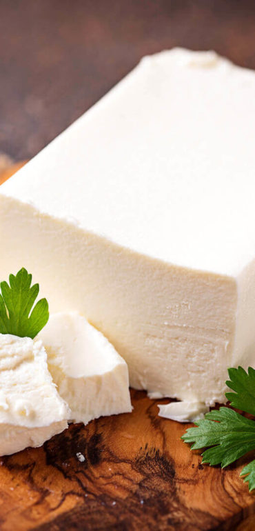 Block of feta cheese with parsley garnish.