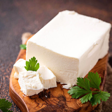 Block of feta cheese with parsley garnish.