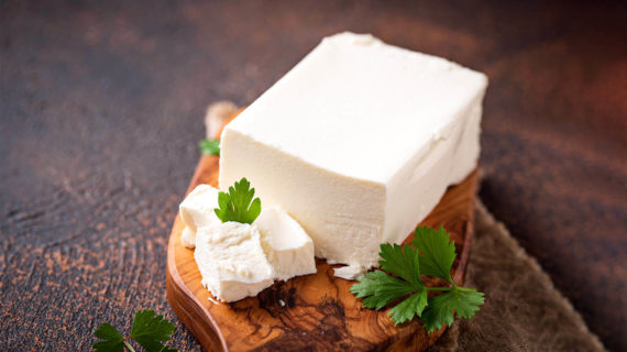 Block of feta cheese with parsley garnish.