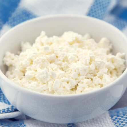Bowl of cottage cheese on blue cloth.