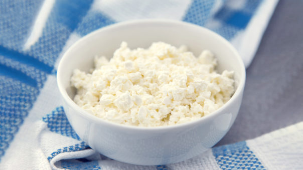 Bowl of cottage cheese on blue cloth.