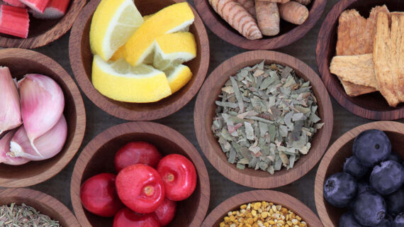 Assorted herbs and fruits in wooden bowls.
