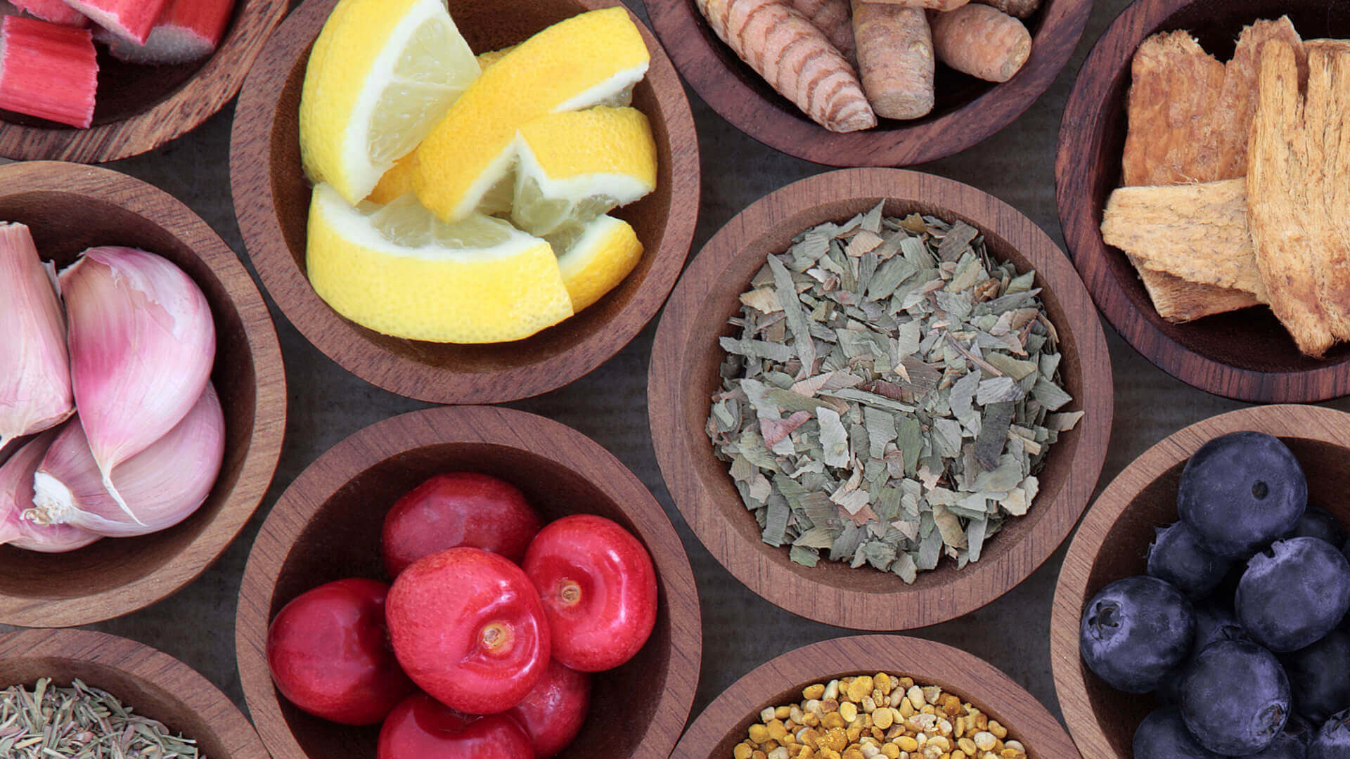 Assorted herbs and fruits in wooden bowls.