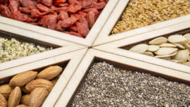 Assorted seeds and nuts in wooden sections.