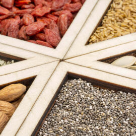 Assorted seeds and nuts in wooden sections.