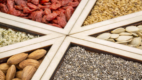 Assorted seeds and nuts in wooden sections.