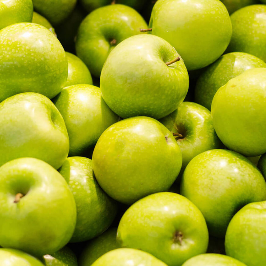 Green apples piled together in close-up.
