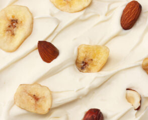 Yogurt topped with banana chips and nuts.