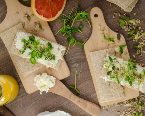 Crackers with cheese and sprouts on boards.